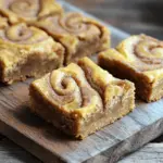 To make these tasty blondies, you will need: - 1 cup unsalted butter, melted - 1 cup packed brown sugar - 1/2 cup granulated sugar - 2 large eggs - 2 teaspoons vanilla extract - 2 cups all-purpose flour - 1 teaspoon baking powder - 1/2 teaspoon baking soda - 1/2 teaspoon salt - 2 teaspoons ground cinnamon - 1/4 teaspoon nutmeg - 1/4 cup granulated sugar (for topping) - 1 tablespoon ground cinnamon (for topping) Each ingredient plays a key part in making these blondies great: - Unsalted butter: Adds richness and moisture. It helps create a soft texture. - Brown sugar: Gives a deeper flavor and helps keep the blondies chewy. - Granulated sugar: Balances sweetness and contributes to a light texture. - Eggs: Bind the ingredients and add moisture. - Vanilla extract: Enhances flavor and adds warmth. - All-purpose flour: Provides structure. It holds everything together. - Baking powder and baking soda: These leavening agents make the blondies rise and stay soft. - Salt: Balances sweetness and enhances flavors. - Ground cinnamon and nutmeg: These spices give that signature snickerdoodle flavor, making every bite delightful. You can swap some ingredients if needed: - Unsalted butter: Use coconut oil for a dairy-free option. - Brown sugar: You can use coconut sugar for a healthier choice. - Eggs: Replace each egg with 1/4 cup unsweetened applesauce for a vegan option. - All-purpose flour: Almond flour can be used for a gluten-free version. - Granulated sugar: You can use honey or maple syrup, but adjust the liquid in the recipe. These substitutions allow you to enjoy these blondies with different diets or preferences. For the full recipe, click here. Start by preheating your oven to 350°F (175°C). Line a 9x13 inch baking dish with parchment paper. Leave some paper hanging over the edges. This helps with easy removal later. In a large bowl, mix the melted butter, brown sugar, and granulated sugar. Stir until it looks smooth and well combined. Next, add the eggs and vanilla extract. Mix until everything is fully mixed together. In another bowl, whisk the flour, baking powder, baking soda, salt, ground cinnamon, and nutmeg. Combine these dry ingredients slowly into the wet mix. Stir gently until just combined. Don’t overmix, or your blondies may become tough. For the cinnamon swirl, mix the remaining granulated sugar and cinnamon in a small bowl. Pour half of the blondie batter into your prepared baking dish. Use a spatula to spread it evenly. Now, sprinkle half of the cinnamon-sugar mix over this layer. Then, add the rest of the batter on top. Gently swirl the batter with a knife to create a marbled look. Finally, sprinkle the remaining cinnamon-sugar mix over the top. Bake your blondies in the preheated oven for 25-30 minutes. Check for readiness by inserting a toothpick into the center. It should come out clean. After baking, let the blondies cool in the pan for about 10 minutes. Use the parchment paper to lift them out. Place them on a wire rack to cool completely. Once cooled, cut the blondies into squares. You can serve them plain or with a scoop of ice cream on top. For extra flair, drizzle with caramel sauce if you like. Enjoy these sweet treats! For the full recipe, check the earlier section. To get the best texture, start with melted butter. This helps create a rich, soft base. Mix the sugars with the melted butter until smooth. This ensures even sweetness. Don't overmix your batter. Stir until just combined to keep your blondies soft and chewy. Add a hint of nutmeg for warmth. It pairs well with cinnamon and adds depth. Use high-quality vanilla extract for a richer taste. Consider sprinkling sea salt on top before baking. It enhances the sweet and spicy flavors, giving a nice crunch. One common mistake is overbaking. Keep an eye on them in the oven. A toothpick should come out with a few moist crumbs, not clean. Also, don’t skip lining the pan with parchment paper. This makes removal easy and prevents sticking. For the perfect swirl, be gentle when mixing in the cinnamon-sugar. Too much mixing can ruin the beautiful swirls. For complete instructions, check out the Full Recipe. {{image_2}} You can play with the flavors in these blondies. Try adding white chocolate chips for a sweet twist. You can also mix in chopped nuts like pecans or walnuts for a crunchy texture. If you enjoy fruit, diced apples or pears can add a nice freshness. For a more festive touch, add a pinch of nutmeg or ginger for warmth. Get creative with your toppings. Instead of the cinnamon-sugar mix, drizzle caramel sauce over the top after baking. You can also sprinkle coarse sea salt for a sweet and salty flavor. If you love chocolate, adding dark chocolate chunks will make them extra indulgent. Dried cranberries or cherries can add a tart bite. Experiment and make these blondies your own! To make these blondies gluten-free, swap the all-purpose flour for a gluten-free blend. Just make sure it contains xanthan gum for the right texture. For a vegan version, replace eggs with flax eggs (one tablespoon of ground flaxseed mixed with three tablespoons of water). Use coconut oil instead of butter for richness. You can also find vegan butter to keep the flavor intact. With these adaptations, everyone can enjoy this delightful treat! For the full recipe, check out the recipe section above. To keep your cinnamon swirl snickerdoodle blondies fresh, store them in an airtight container. This helps prevent them from drying out. You can keep them at room temperature for up to three days. If you want them to last longer, consider refrigerating them. Just be sure to allow them to cool completely before you store them. Freezing your blondies is a great way to save them for later. First, cut them into squares. Wrap each square tightly in plastic wrap. Then, place the wrapped squares in a freezer bag. You can freeze them for up to three months. When you're ready to enjoy, just thaw them in the fridge overnight. If you have leftovers, you might want to reheat them for a warm treat. Preheat your oven to 350°F. Place the blondies on a baking sheet and cover them with foil. Heat them for about 10 minutes. You can also microwave a square for about 15-20 seconds. Enjoy them warm for that fresh-baked taste! Cinnamon swirl snickerdoodle blondies are soft, chewy treats. They combine the flavors of classic snickerdoodles with a rich blondie base. The cinnamon swirl adds a sweet twist, making them extra special. These blondies are perfect for sharing or enjoying on your own. You can find the full recipe above to create these delightful desserts. Yes, you can use brown sugar in place of granulated sugar. Brown sugar adds moisture and a rich flavor. This swap will make your blondies even chewier and more flavorful. Just remember, if you use more brown sugar, you might need to adjust other ingredients slightly. Cinnamon swirl snickerdoodle blondies last about 5 days at room temperature. Store them in an airtight container to keep them fresh. You can also refrigerate them for longer storage. If you freeze them, they can last up to three months. If your blondies turn out dry, you may have overbaked them. Make sure to check them a few minutes early next time. You can also add a little extra butter or even a splash of milk to improve moisture. Don't worry; they will still taste great! Cinnamon Swirl Snickerdoodle Blondies are easy to make and fun to enjoy. You learned about each ingredient’s role, baking steps, and ways to enhance flavor. You also discovered tips to avoid common mistakes and variations to try. Remember to store leftovers properly and feel free to freeze for later. These blondies are a tasty treat for everyone, so get baking! Enjoy your sweet creation and share it with friends!