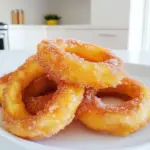 To make these tasty cinnamon sugar apple rings, gather the following: - 2 large apples (Honeycrisp or Granny Smith are great) - 1/2 cup all-purpose flour - 1 teaspoon baking powder - 1/4 teaspoon salt - 1 teaspoon ground cinnamon - 1/4 cup granulated sugar - 1/3 cup milk (almond or oat milk works too) - 1 large egg - 1/2 teaspoon vanilla extract - Cooking spray or oil for the air fryer If you need to make swaps, here are some ideas: - Use gluten-free flour instead of all-purpose flour. - Swap the egg for a flax egg (1 tablespoon flaxseed meal + 2.5 tablespoons water). - Choose dairy-free milk to keep it vegan. Choosing the right apples is key for great flavor. Here are my top tips: - Pick firm apples; they hold their shape when cooked. - Honeycrisp apples add sweetness and crunch. - Granny Smith apples give a nice tart flavor. - Avoid soft or overripe apples; they can turn mushy. First, wash and dry your apples. I like to use Honeycrisp or Granny Smith for their sweet and tart taste. Next, remove the core. You can use an apple corer or a knife. After that, slice the apples into 1/4-inch thick rings. This thickness ensures they cook evenly and get crispy. In a mixing bowl, combine the flour, baking powder, salt, and ground cinnamon. This gives the rings extra flavor. In another bowl, whisk the milk, egg, and vanilla extract until they blend well. Pour the wet mix into the dry mix. Stir until you have a smooth batter. It should be thick but easy to pour. Preheat your air fryer to 350°F (175°C). While it heats up, spray the basket with cooking spray or brush it with oil. Dip each apple ring into the batter, making sure they are fully coated. Shake off any extra batter before placing them in the air fryer. Lay them in a single layer, avoiding crowding. You may need to work in batches. Air fry the apple rings for 8-10 minutes. Flip them halfway through for even crispiness. While the apple rings cook, mix the granulated sugar and remaining ground cinnamon in a small bowl. Once the apple rings are golden brown and crisp, take them out of the air fryer. Toss the hot apple rings in the cinnamon sugar mixture until they are well coated. This step adds a sweet crunch that makes them a delightful treat. To make your apple rings crispy, follow a few key steps. First, slice your apples into 1/4-inch thick rings. Thinner slices cook faster and get crispier. Use a good amount of batter to coat each ring. This helps create a crunchy layer. Air fry at 350°F (175°C) for 8-10 minutes. Flip them halfway through for even cooking. You can also check for doneness by looking for a golden color. Preventing sticking is easy with a few tricks. Make sure to spray the air fryer basket with cooking spray before adding the apple rings. This will create a non-stick surface. Be sure not to overcrowd the basket. Leave space between each ring so hot air can flow freely. If they do stick, use a spatula to gently lift them. Air fryers can vary in size and power. If you have a smaller model, cook fewer apple rings at once. You may need to adjust the cooking time too. Some air fryers cook faster than others. Start by checking your apple rings a minute or two early. If they're not golden yet, close the basket and check every minute. This way, you can avoid overcooking. {{image_2}} You can easily change the flavor of your cinnamon sugar apple rings. Try adding a pinch of nutmeg for warmth. A dash of ginger gives a nice spice kick. You can also fold in some chopped nuts for crunch. If you like chocolate, sprinkle cocoa powder into the batter. This twist makes a unique treat! If you want a healthier version, swap out granulated sugar. Try using honey or maple syrup instead. These options add a natural sweetness. You can also use stevia or monk fruit sweetener for a low-calorie choice. Adjust the amounts based on your taste. Always remember to mix well to ensure everything blends. Apples are great, but you can try other fruits too! Pears work well and have a soft texture. Peaches bring a juicy flavor that pairs nicely with cinnamon. Bananas can also be used for a sweet twist. Just slice them thick and follow the same steps. Each fruit gives a new taste to this fun recipe! Once you finish your tasty apple rings, let them cool completely. Place them in an airtight container. Store them in the fridge for up to three days. This keeps them fresh and ready for snacking. To bring back the crunch, reheat the apple rings in the air fryer. Set the air fryer to 350°F (175°C). Heat them for about 3-5 minutes. This method keeps them crispy, just like fresh. If you want to save some for later, freezing works great. After cooling, lay the apple rings in a single layer on a baking sheet. Freeze them for about an hour. Once frozen, transfer them to a freezer bag. They can last up to three months in the freezer. When you're ready to enjoy, just reheat them in the air fryer as mentioned. Yes, you can use different types of flour. If you want a gluten-free option, try almond or coconut flour. Each flour gives a unique taste and texture. Just remember that the thickness of the batter may change. You may need to adjust the liquid you add. Experiment with what you have on hand! To make these apple rings without an air fryer, use a regular oven or a skillet. If using the oven, preheat it to 400°F (200°C). Place the battered apple rings on a baking sheet. Bake for 15-20 minutes, flipping halfway through. If using a skillet, heat oil over medium heat. Fry the apple rings for 2-3 minutes per side until golden brown. Cinnamon sugar apple rings pair well with many things. You can serve them with vanilla ice cream or whipped cream for a sweet treat. They also go great with yogurt for a light snack. Consider adding a drizzle of caramel sauce for extra flavor. Enjoy them as a dessert or a fun breakfast! To sum up, we explored how to make delicious air-fried apple rings. You learned about key ingredients, tips for selecting apples, and neat substitutions for diets. The step-by-step guide makes the process simple. We covered ways to ensure crispiness and avoid sticking in the air fryer. Variations give you room for creativity and fun. Finally, proper storage helps keep your treats fresh. Enjoy experimenting with this recipe and make it your own!