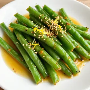 For this dish, I use 1 pound of fresh green beans. Make sure they are bright green and firm. Trim the ends off to prepare them. Fresh green beans add crunch and flavor. Blanching them helps keep their color and taste. Next, I use 4 cloves of garlic, minced. Garlic gives a strong, tasty kick. I also add 4 tablespoons of unsalted butter. The butter adds richness to the dish. For a bit of heat, you can include 1 teaspoon of red pepper flakes. Salt and pepper are essential for seasoning. For extra flavor, I often add 1 tablespoon of soy sauce. You can use tamari for a gluten-free option. I also squeeze in 1 tablespoon of lemon juice for brightness. The zest of 1 lemon adds a fresh twist. Finally, I like to sprinkle toasted sesame seeds on top. They give a nice crunch and look great on the plate. {{ingredient_image_1}} Start by boiling a pot of salted water. The salt adds flavor. Once the water boils, add 1 lb of fresh green beans, trimmed beforehand. Blanch the beans for 2-3 minutes. You want them bright green and slightly tender. This step helps keep the beans crisp. After blanching, drain the beans and place them in an ice bath. This stops the cooking process and locks in their color. Next, grab a large skillet and set it over medium heat. Add 4 tablespoons of unsalted butter and let it melt. Once the butter is melted, add 4 cloves of minced garlic. If you like a bit of heat, toss in 1 teaspoon of red pepper flakes. Saut&eacute; the garlic for about 1 minute. Keep an eye on it so it doesn&rsquo;t burn. You want to smell that wonderful aroma! Now, it&rsquo;s time to add the blanched green beans to the skillet. Toss the beans in the garlic butter until they are well coated. Increase the heat to medium-high and saut&eacute; for another 5-7 minutes. This will make them crispy-tender. Season the beans with salt, pepper, 1 tablespoon of soy sauce, and 1 tablespoon of lemon juice. Toss everything well to combine. Let it cook for another minute. Finally, add the zest of 1 lemon for a bright finish. Serve the beans on a platter and sprinkle with toasted sesame seeds for crunch. Enjoy your crispy garlic butter green beans! To keep your green beans crisp, start with fresh ones. Choose bright green beans without blemishes. Blanching helps too. Boil them for just 2-3 minutes. Then, quickly dunk them in ice water. This process stops cooking and locks in that vibrant green color. Always drain them well before cooking. If you leave water on, they can get soggy. Flavor is key to great green beans. Start with garlic in butter. Saut&eacute; the minced garlic until it smells good, but don&rsquo;t burn it. Add red pepper flakes for a kick if you like. Soy sauce gives umami depth. A squeeze of lemon juice adds brightness. Mixing in lemon zest at the end brings a fresh touch. Try toasted sesame seeds for a nutty crunch on top. If you have leftovers, store them in an airtight container. Put them in the fridge for up to three days. Reheat them on the stove for best results. Just add a little butter or olive oil. This helps them regain some of their crispness. Avoid microwaving, as it can turn them mushy. Enjoy your tasty green beans again! Pro Tips Blanching is Key: Blanching the green beans not only preserves their vibrant color but also helps maintain their crunchiness. Make sure to transfer them to an ice bath immediately after boiling! Adjust the Heat: If you prefer a spicier dish, feel free to increase the amount of red pepper flakes. Conversely, for a milder flavor, you can omit them altogether or reduce the quantity. Fresh Garlic for Best Flavor: Using fresh garlic instead of pre-minced garlic will greatly enhance the flavor of your dish. The aroma of freshly minced garlic is unbeatable! Experiment with Garnishes: While toasted sesame seeds add a lovely crunch, consider trying other garnishes like crushed peanuts or a sprinkle of freshly grated Parmesan for a unique twist. {{image_2}} You can easily enhance your crispy garlic butter green beans by adding protein. Shrimp and chicken work great. For shrimp, just toss it in the skillet after saut&eacute;ing the garlic. Cook until it turns pink, then add the green beans. For chicken, cut it into small pieces. Saut&eacute; the chicken first until it&rsquo;s cooked through, then add the green beans and garlic. This makes the dish heartier and adds a new flavor. If you prefer a vegetarian option, tofu is a fantastic choice. You can use firm or extra-firm tofu. First, press the tofu to remove excess moisture. Cut it into cubes and saut&eacute; it in the skillet before adding the garlic. Cook until golden brown, then add the green beans. This adds a nice texture and protein to your meal while keeping it meat-free. Want to change the heat level? It&rsquo;s simple! If you love heat, add more red pepper flakes when saut&eacute;ing the garlic. You can also toss in some sliced fresh chili for extra spice. If you want less heat, skip the red pepper flakes altogether. You can even add a pinch of sugar to balance the flavors. This lets you customize the dish to suit your taste. To keep your crispy garlic butter green beans fresh, store them in the fridge. Place them in an airtight container. They stay good for about 3 to 4 days. If you want to keep the beans crisp, do not cover them tightly. Moisture can make them soggy. Freezing is a great option if you want to save these beans for later. First, let them cool completely. Spread the beans in a single layer on a baking sheet. Place the sheet in the freezer for about 1-2 hours. Then, transfer the beans to a freezer bag. They can last for up to 3 months. When you're ready to use them, you can cook them straight from the freezer. To reheat your green beans, use a skillet for the best results. Heat a tablespoon of butter in the skillet over medium heat. Add the green beans and toss them until warmed through. This method helps keep them crispy. You can also microwave them for a quick option, but they may lose some crispness. Just heat them in short bursts to avoid overcooking. To make green beans crispy, you need to blanch them first. Start by boiling water with salt. Add the trimmed green beans for 2-3 minutes. This step helps keep their bright green color. Quickly transfer them to an ice bath to stop cooking. After that, saut&eacute; them in garlic butter over medium-high heat. Cook for 5-7 minutes until they are crispy-tender. The key is to keep the heat high enough for that perfect crunch. Yes, you can use frozen green beans! However, they might not get as crispy. Frozen beans often have more water. To fix this, thaw them completely and drain any excess moisture. Then, follow the same steps for saut&eacute;ing. The flavor will still be good, but fresh beans give the best texture. If you prefer crunch, fresh is the way to go. Crispy garlic butter green beans pair well with many dishes. They make a great side for grilled chicken or steak. You can also serve them with rice or quinoa for a complete meal. For a vegetarian option, try them with tofu or lentils. Adding these beans to any dish adds a nice touch and a burst of flavor. To sum up, this post covered all you need for garlic butter green beans. We explored fresh green beans, garlic, spices, and optional add-ons. You learned how to boil, saut&eacute;, and combine these tasty ingredients. I shared tips for crisp beans and tasty flavoring methods. We also discussed variations, storage, and answered common questions. Enjoy making this dish. It adds crunch and flavor to any meal. You now have all the tools to impress at your next dinner!